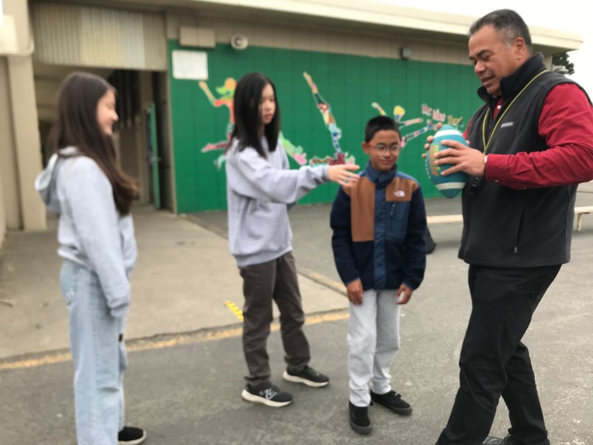 Dyogi is teaching Sophie Yin how to hold a football properly.